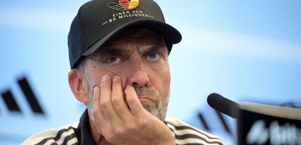 Coach at press conference with hand on face