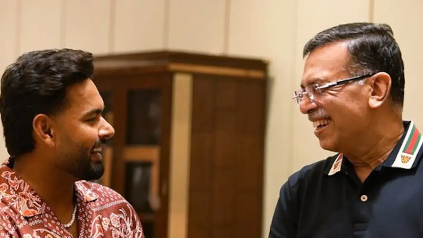 Two men smiling and talking indoors