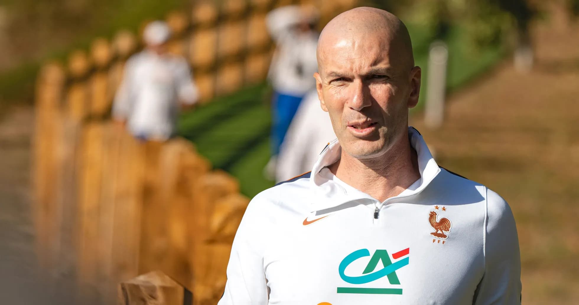 Coach walking near wooden fence during training session