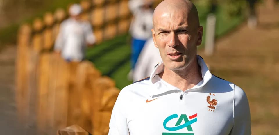 Coach walking near wooden fence during training session