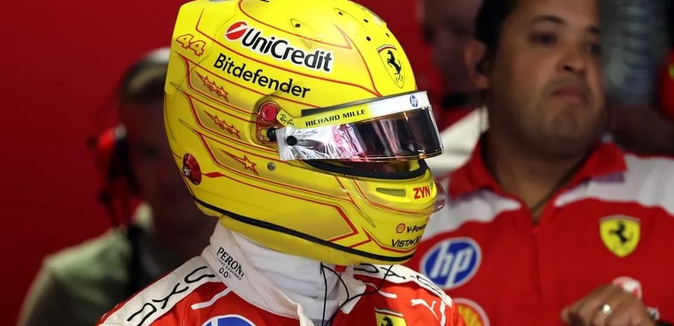 Driver in Ferrari suit wearing helmet in garage