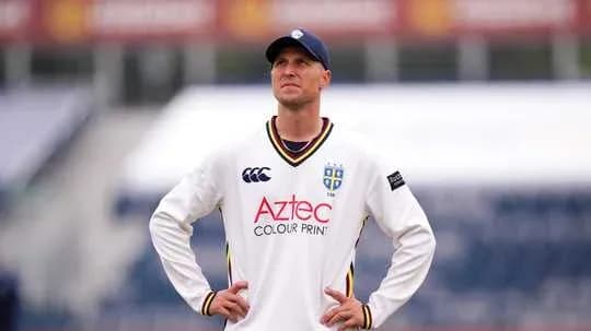 Cricketer in white uniform looking upwards