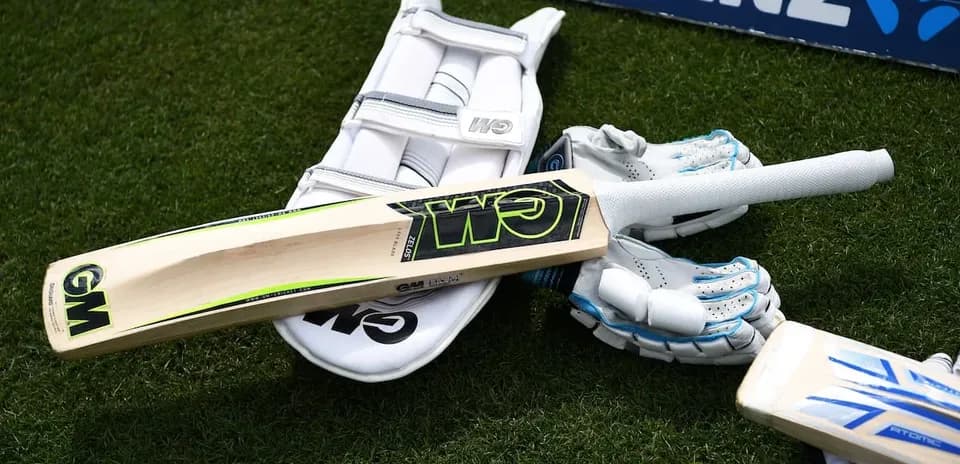 Cricket bat and gloves on grass field