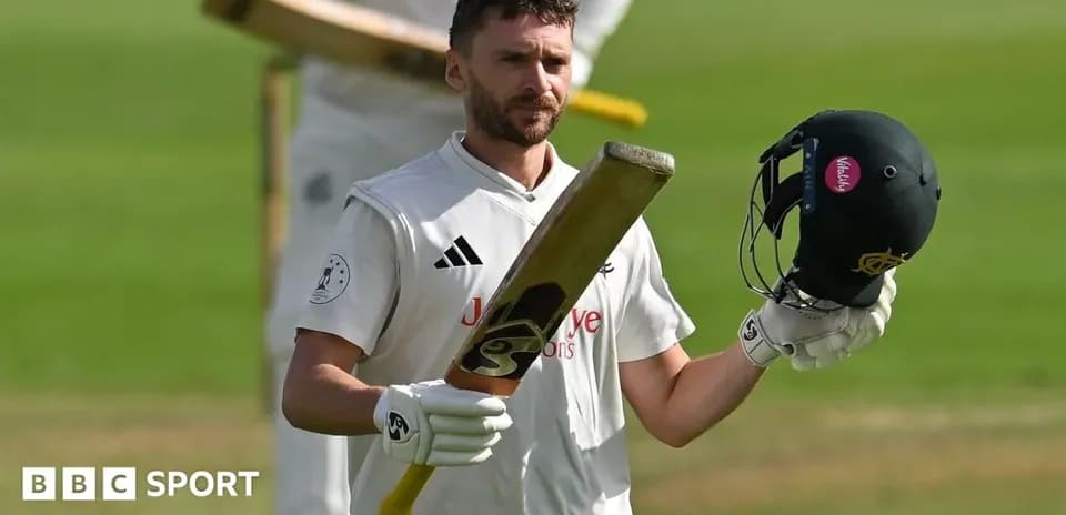 Batsman raising bat and helmet on cricket field