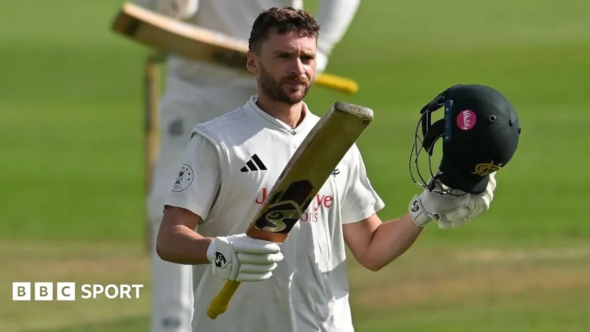 Batsman raising bat and helmet on cricket field