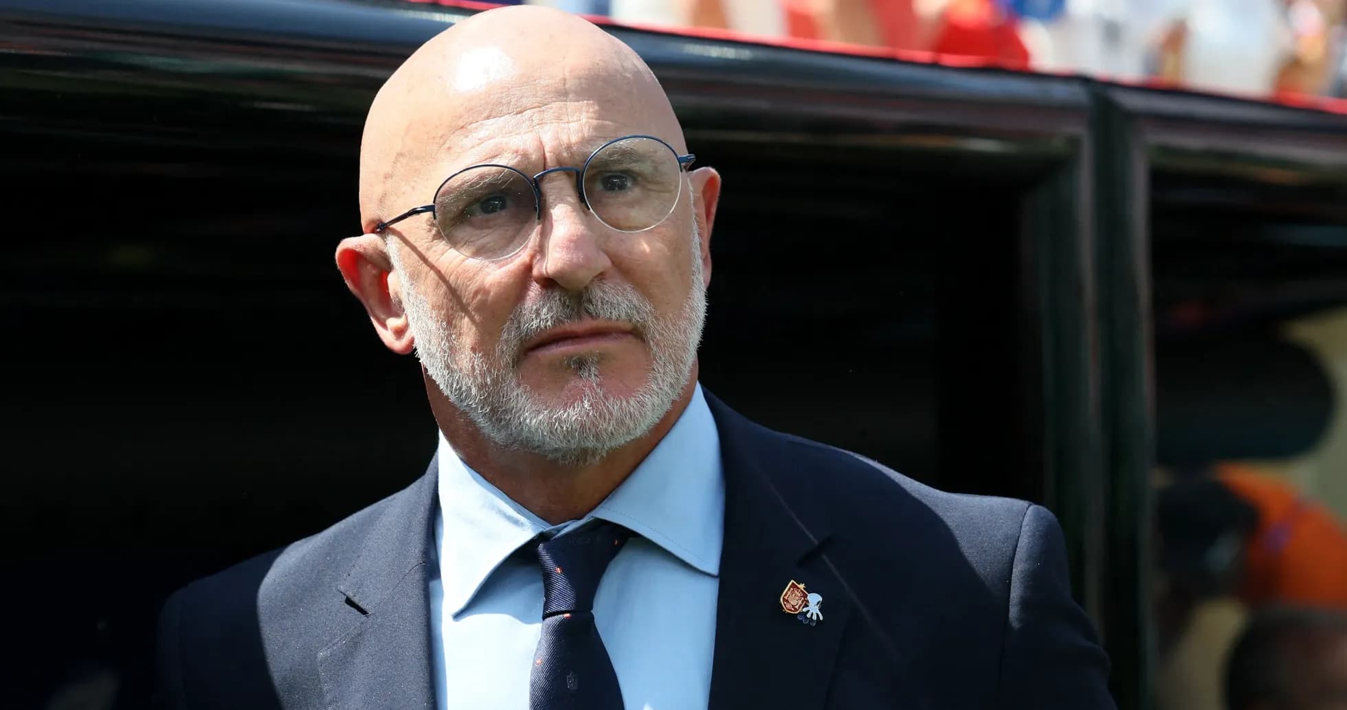Coach wearing glasses standing near team bench