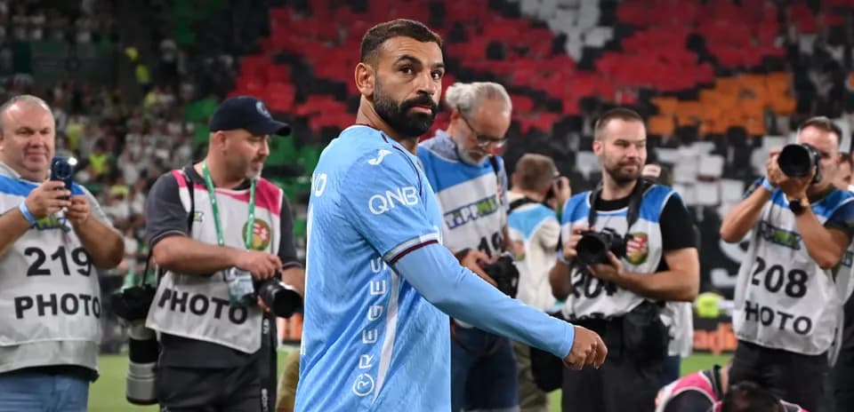 Player walking past photographers on the pitch