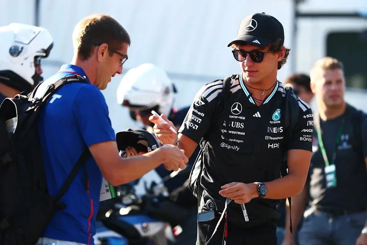 Driver signing autographs for fans in paddock