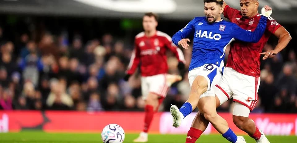 Player in blue jersey challenged by opponent in red