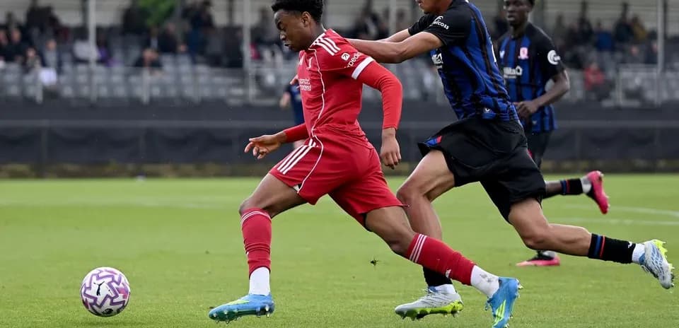 Player in red sprinting while being challenged by opponent