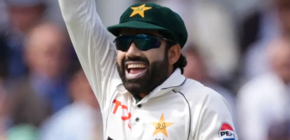 Cricketer celebrating with raised hand on field