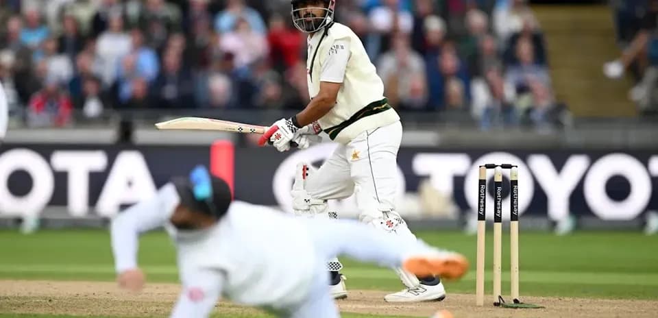 Batsman playing a shot while a fielder dives