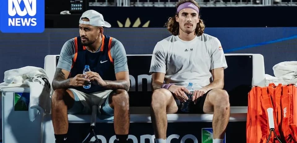Two tennis players sitting on bench during match