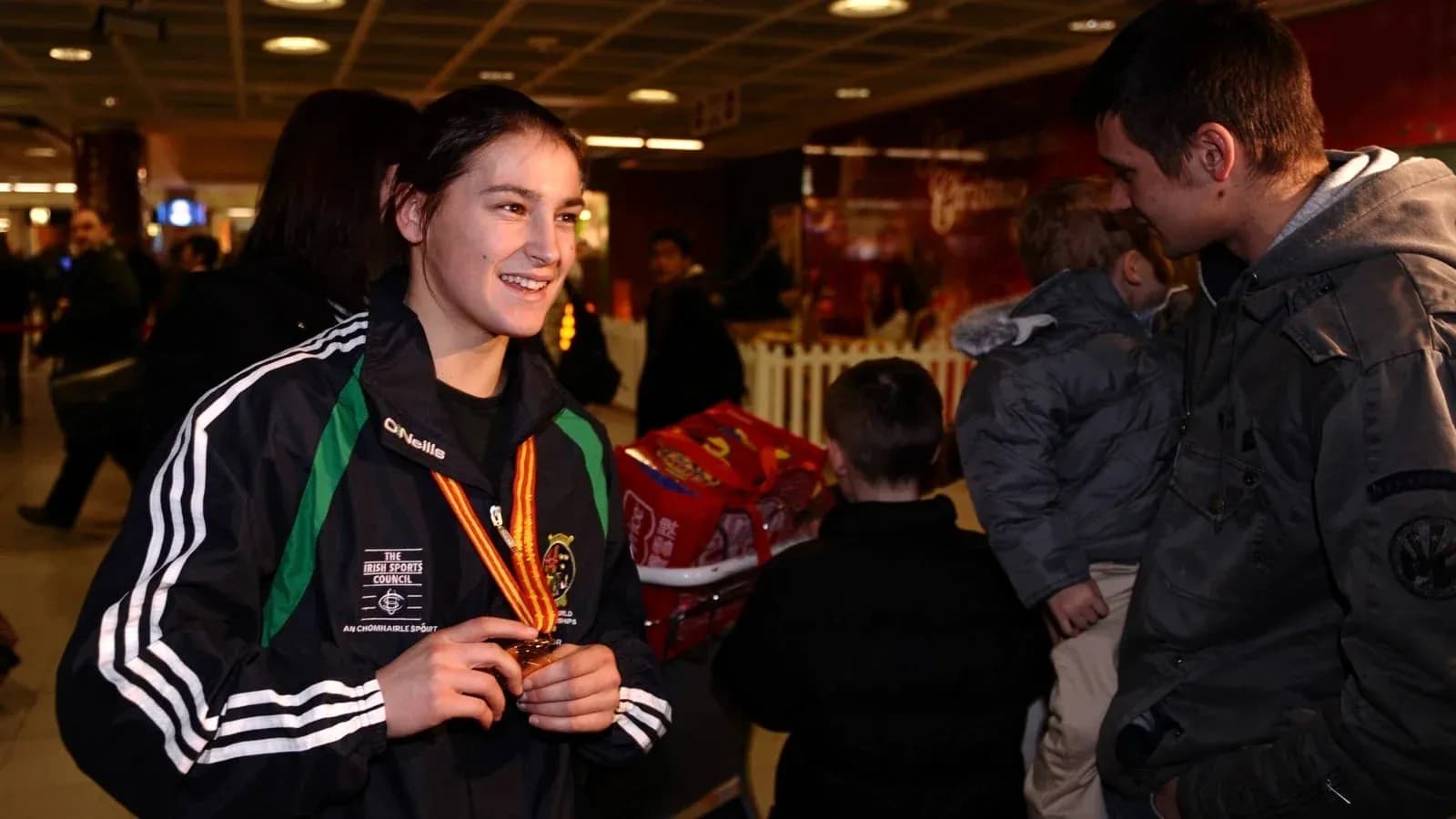 Athlete holding medal in busy airport setting