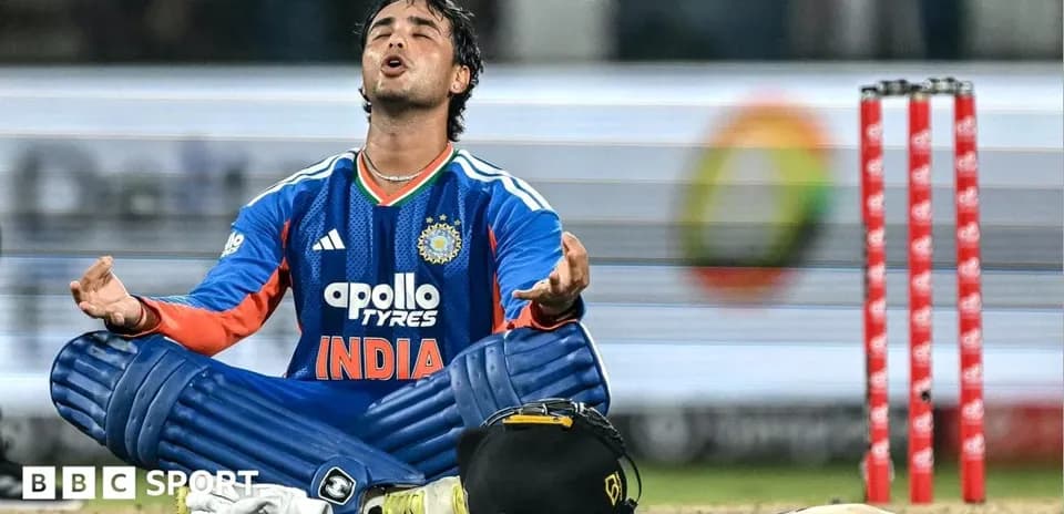 Cricketer in India jersey sitting on pitch