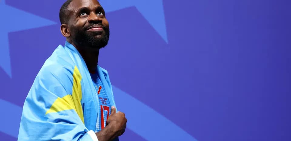 Athlete wrapped in flag, looking upward on stage