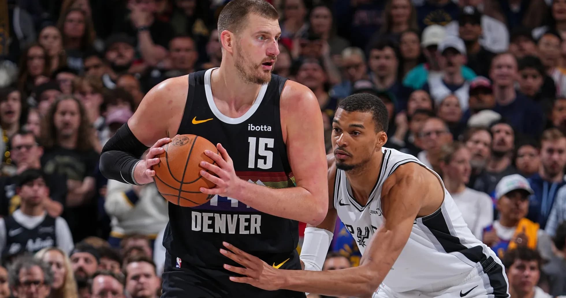 Nikola Jokić holding the ball, guarded by opponent