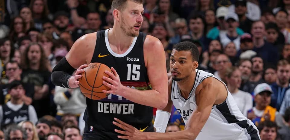 Nikola Jokić holding the ball, guarded by opponent