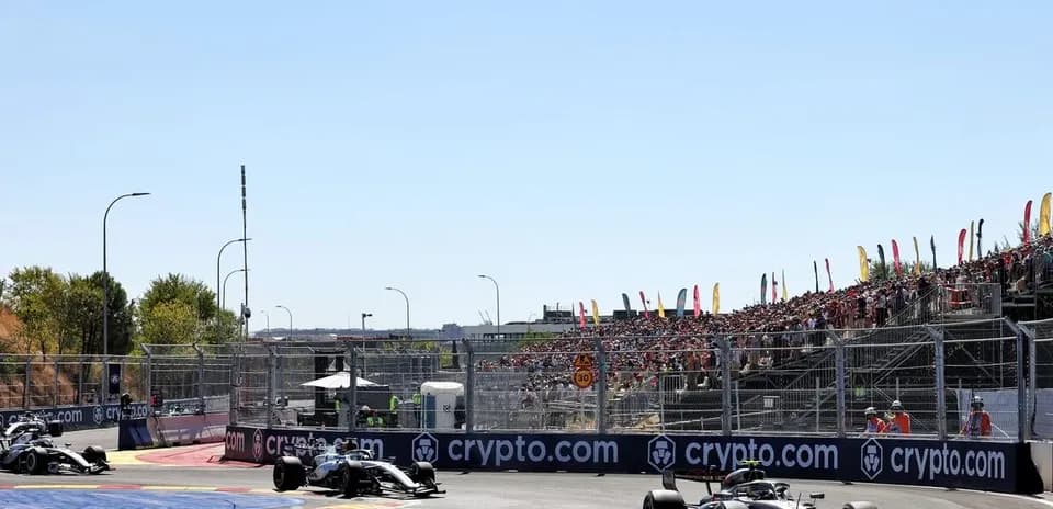 Formula 1 cars racing on track with spectators in background