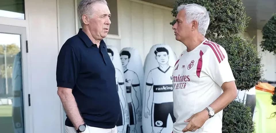 Two coaches talking at training ground with mannequins