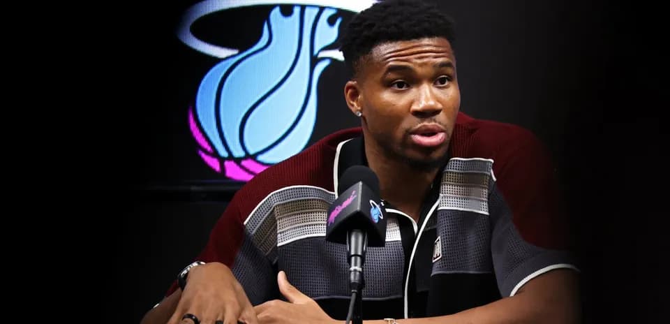 Player speaking at press conference with team logo