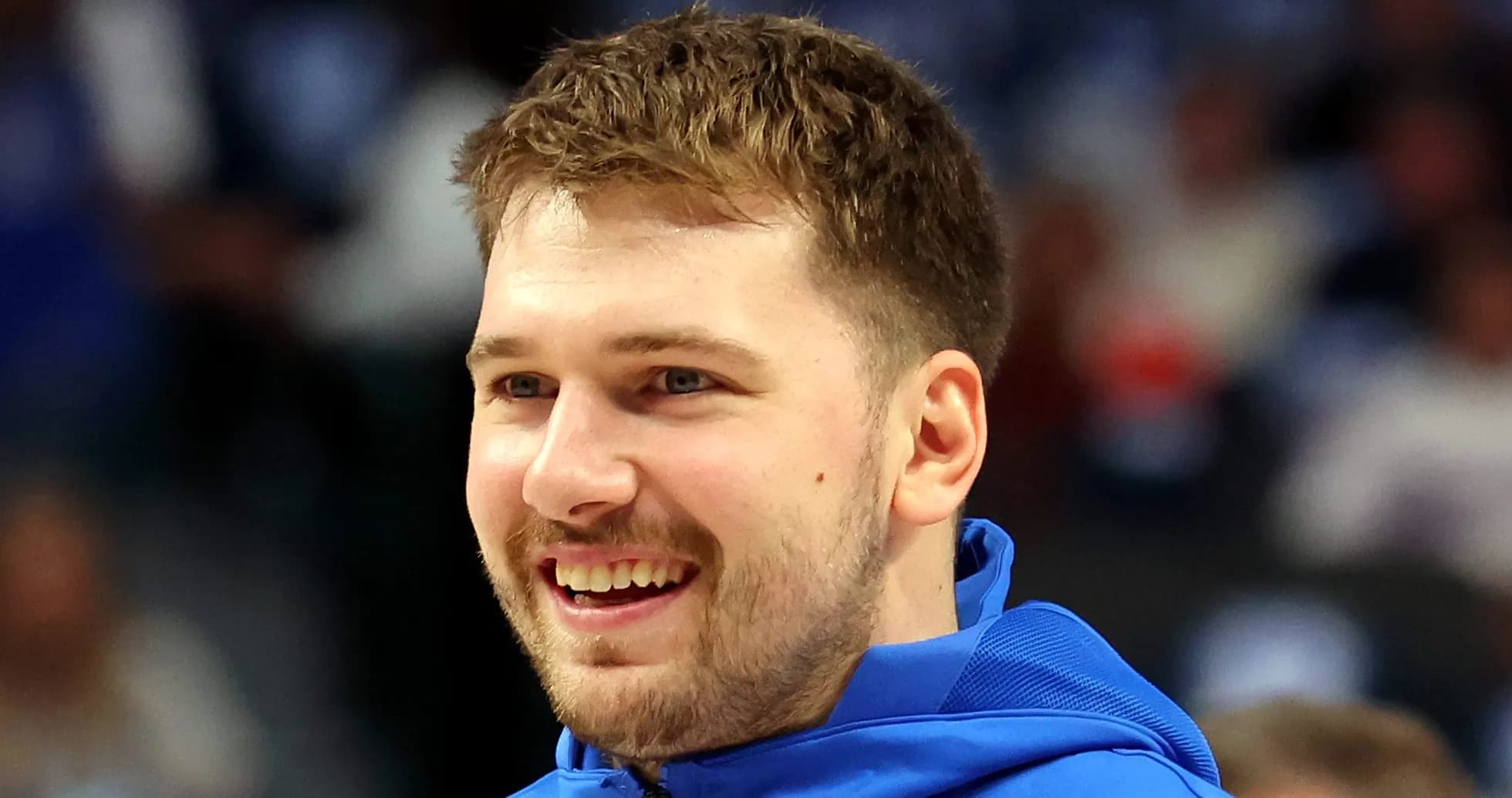 Player smiling in blue warm-up jacket on court