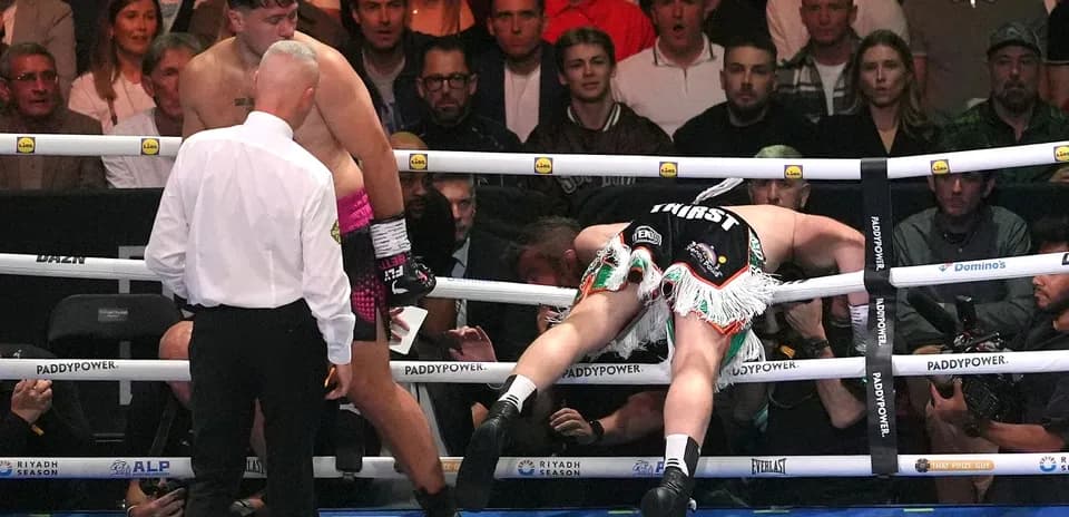 Boxer falling through ropes with referee observing