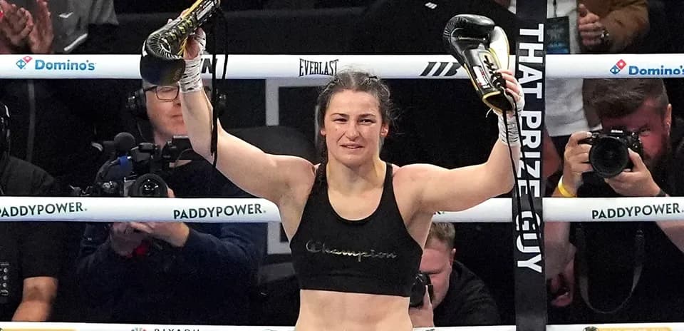 Female boxer celebrating with championship belts in ring