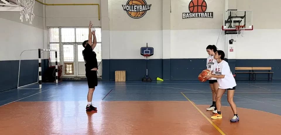 Player shooting basketball while two teammates watch