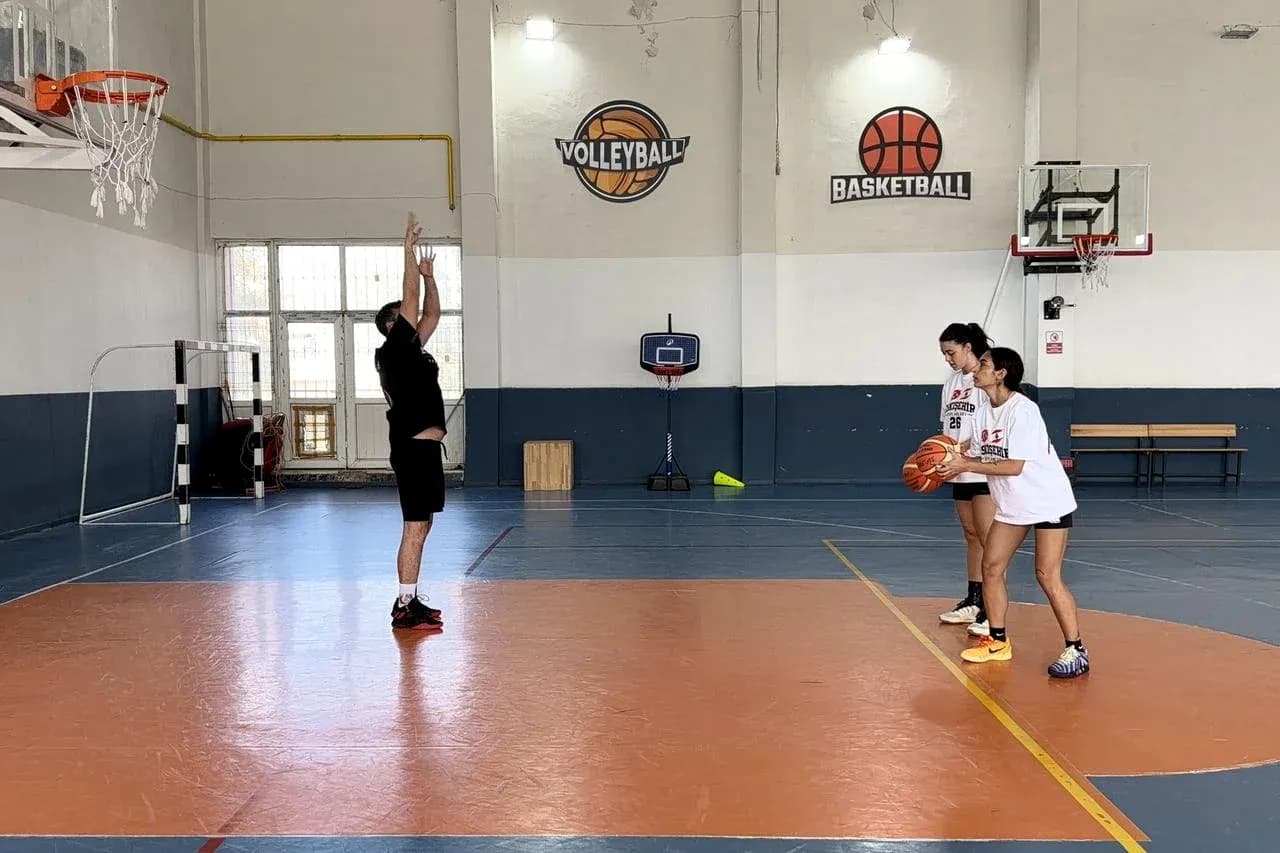 Player shooting basketball while two teammates watch