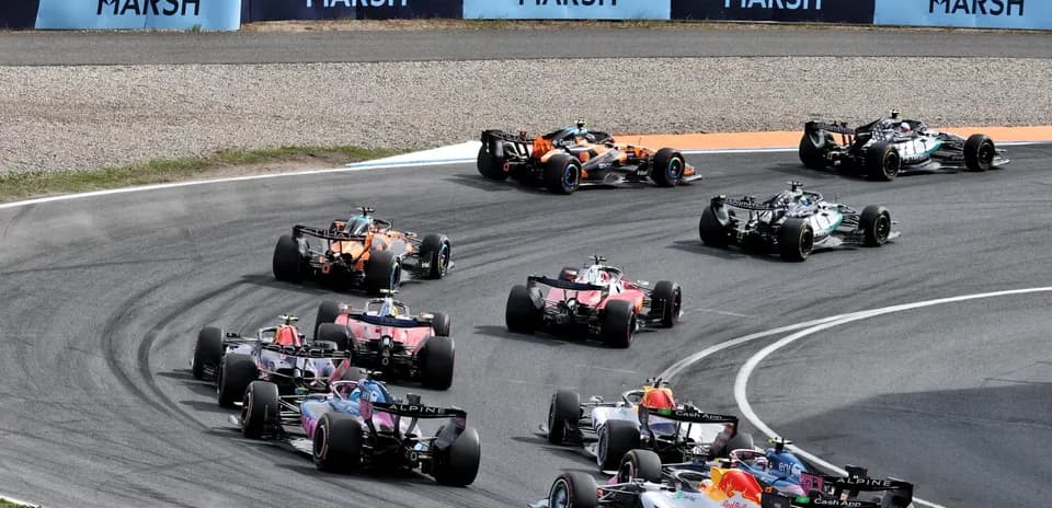 Formula 1 cars racing around a curve on track