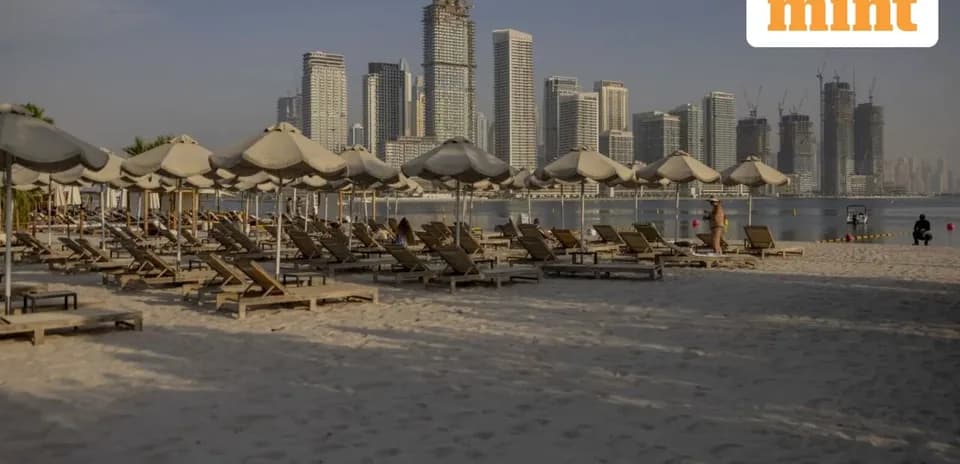 Beach with sun loungers and city skyline in background