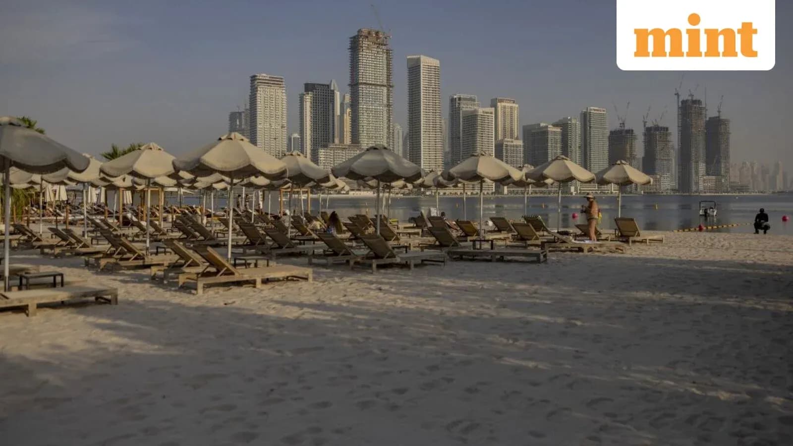 Beach with sun loungers and city skyline in background