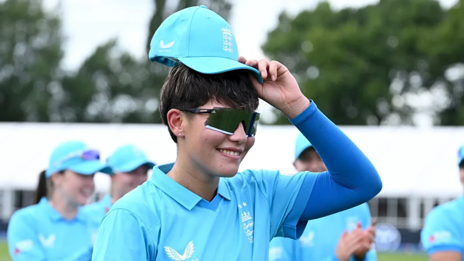 Cricketer adjusting cap during team celebration