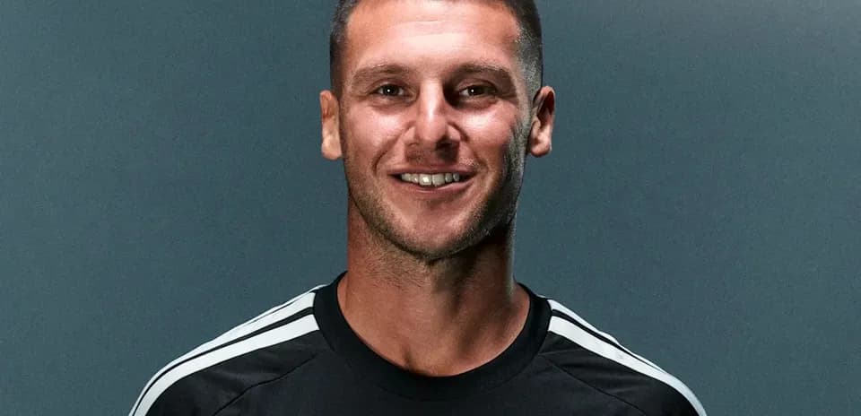 Player posing in black jersey with team logo