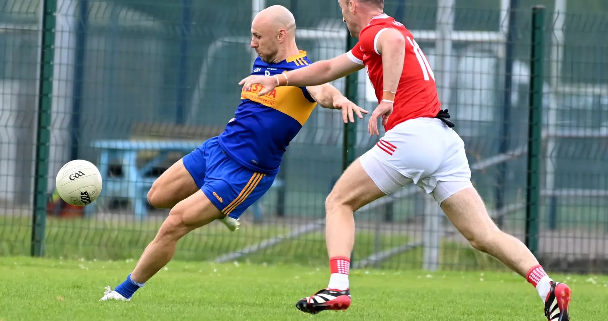 Player kicking a ball while being tackled by opponent