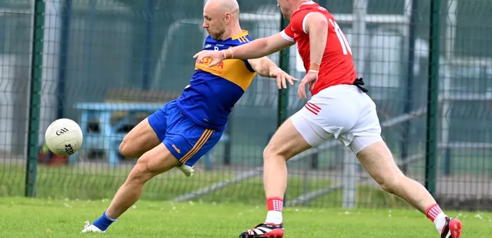 Player kicking a ball while being tackled by opponent