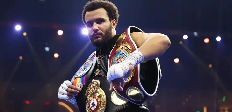 Boxer showcasing championship belts in the ring