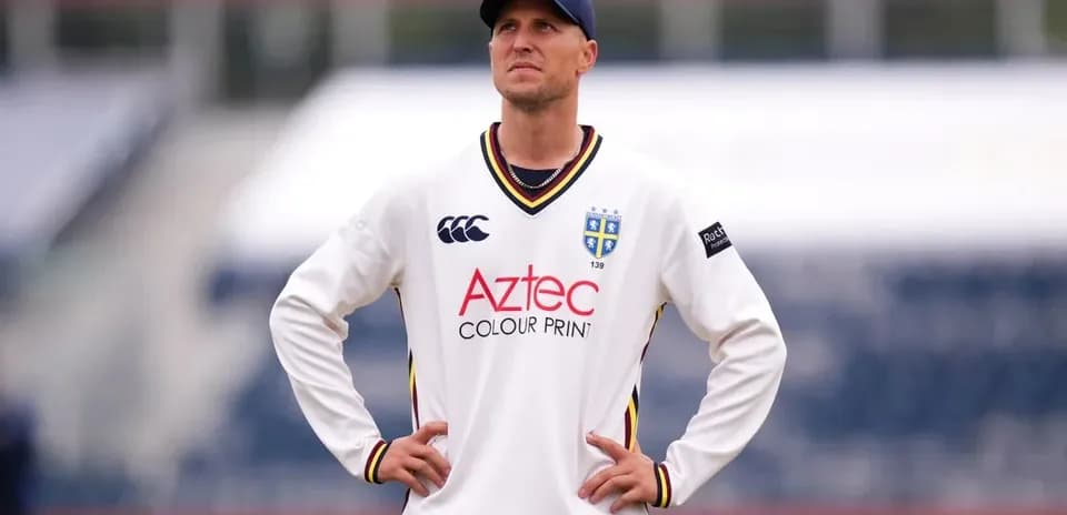 Cricketer in white jersey looking upwards