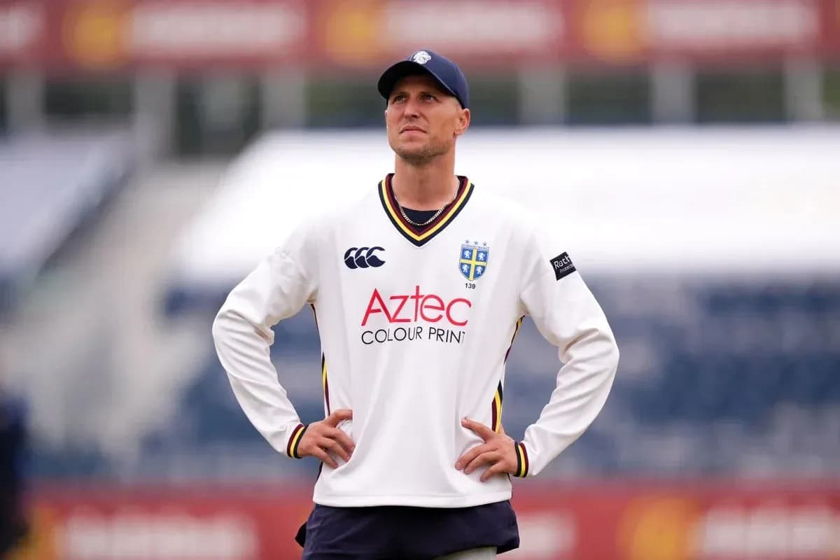 Cricketer in white jersey looking upwards