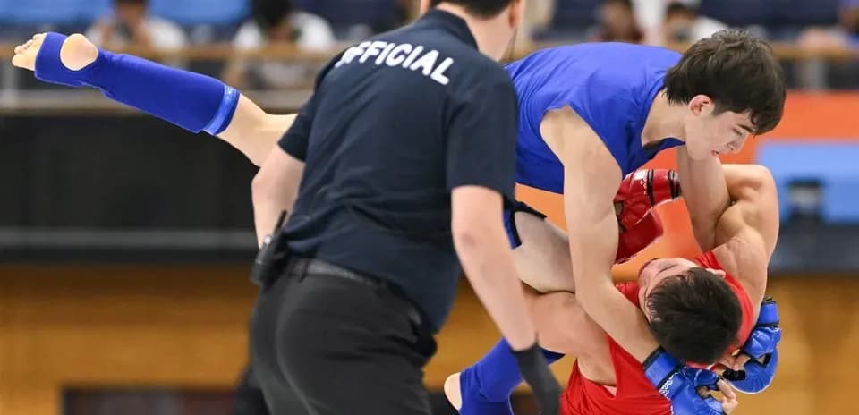 Athletes competing in grappling match with referee present