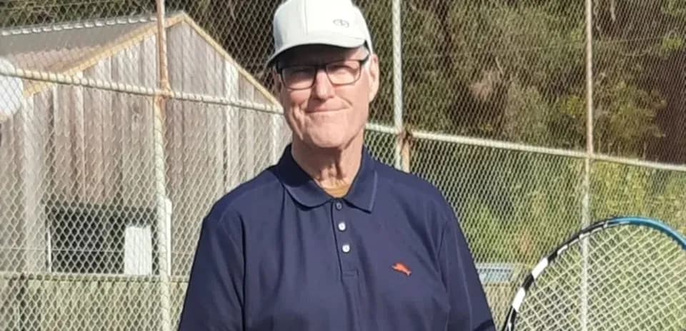 Older man holding a tennis racket on court