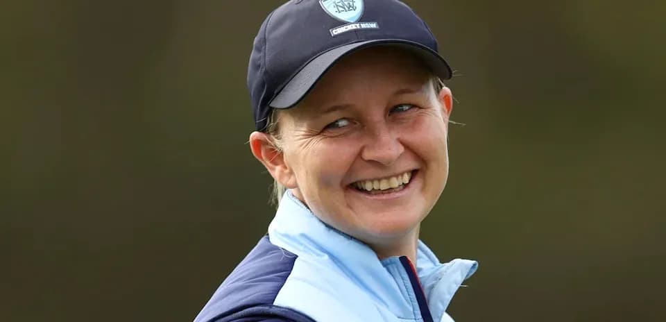 Cricket player smiling in team cap and jacket