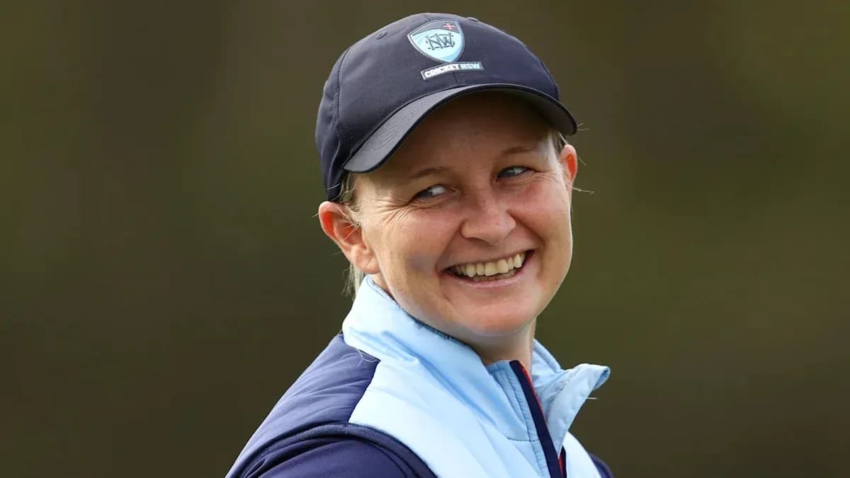 Cricket player smiling in team cap and jacket