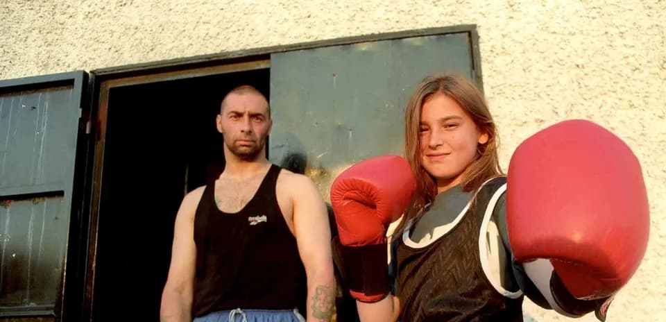 Girl in boxing gloves with trainer standing outside