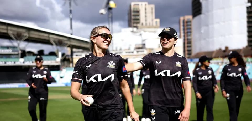 Two cricket players smiling on the field