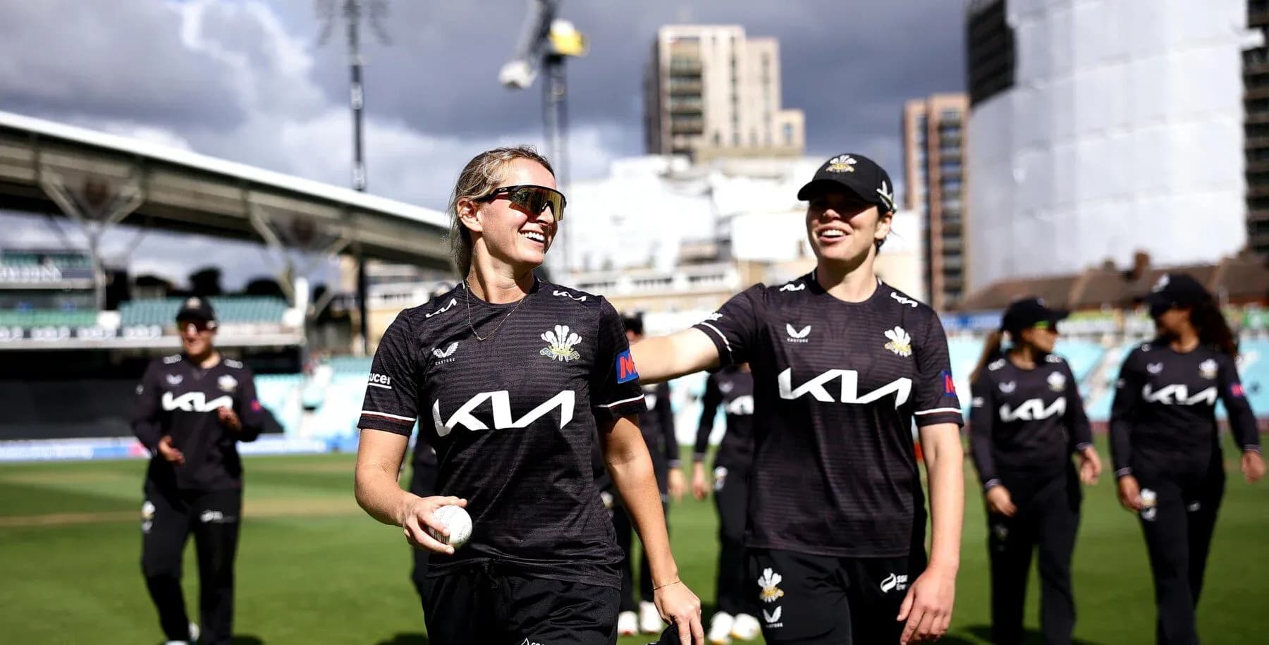 Two cricket players smiling on the field