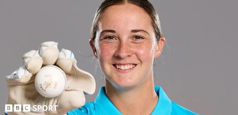 Cricketer holding a ball and smiling at camera