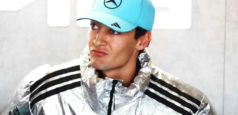 Driver wearing silver jacket and blue cap at event