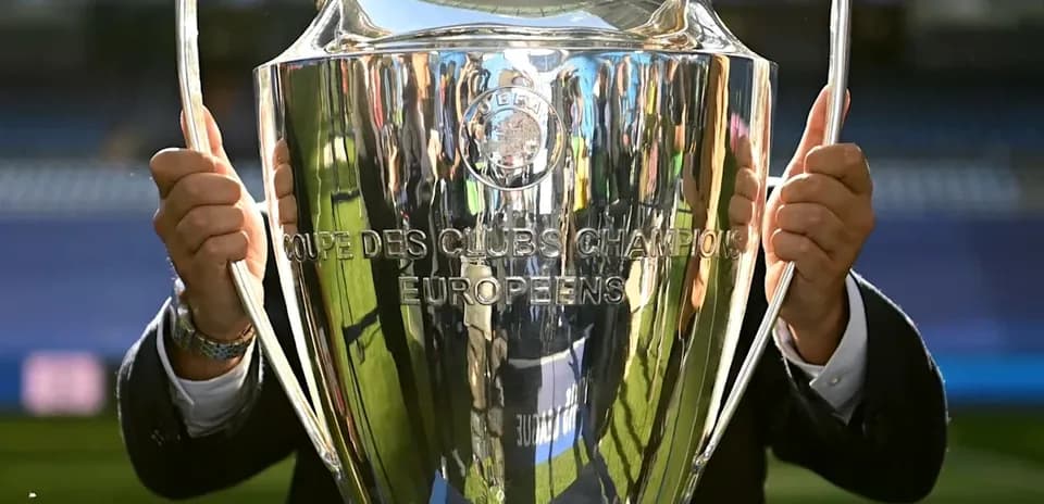 Person holding UEFA Champions League trophy outdoors